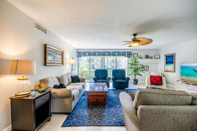 living room with ceiling fan and a textured ceiling