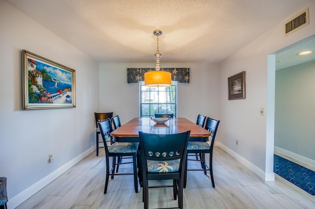 dining area featuring a textured ceiling and light hardwood / wood-style floors