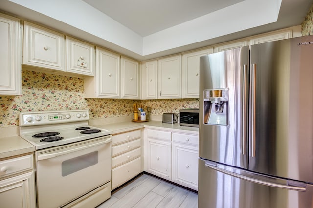 kitchen featuring electric range, cream cabinetry, and stainless steel fridge with ice dispenser