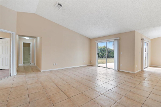 unfurnished room featuring lofted ceiling, light tile patterned floors, and a textured ceiling