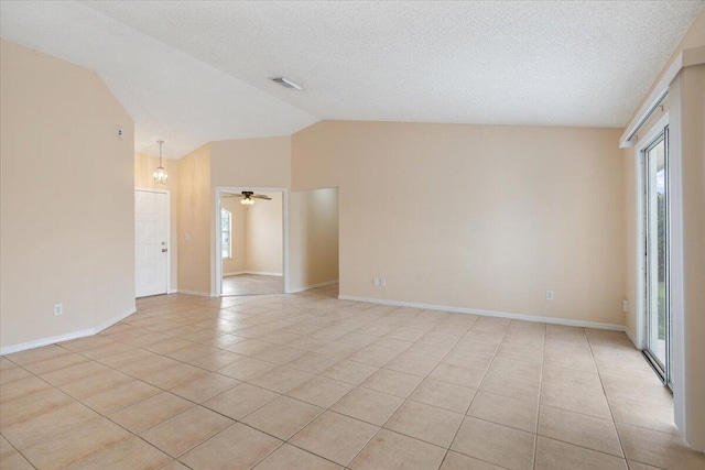 tiled spare room featuring lofted ceiling, ceiling fan, and a textured ceiling