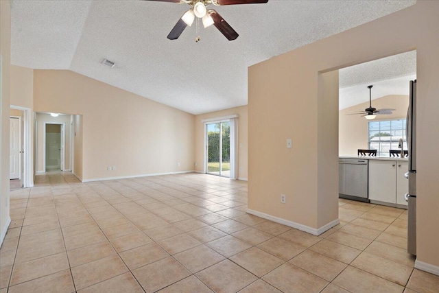 unfurnished room featuring lofted ceiling, a wealth of natural light, a textured ceiling, and light tile patterned floors