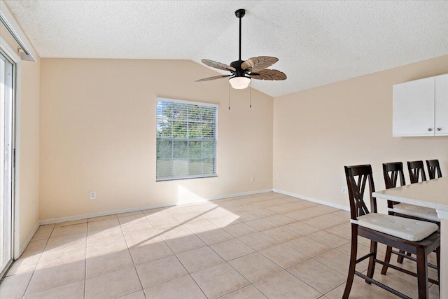 tiled dining room featuring lofted ceiling, a textured ceiling, and ceiling fan