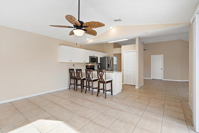 kitchen featuring a breakfast bar, white cabinetry, vaulted ceiling, kitchen peninsula, and stainless steel appliances