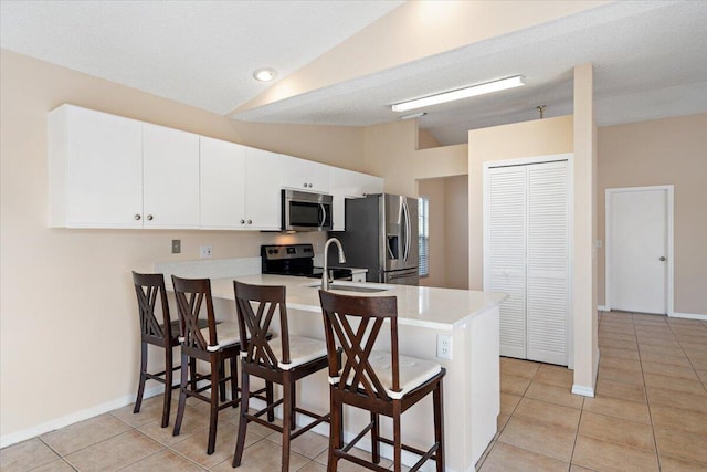 kitchen featuring sink, a breakfast bar area, appliances with stainless steel finishes, white cabinets, and kitchen peninsula