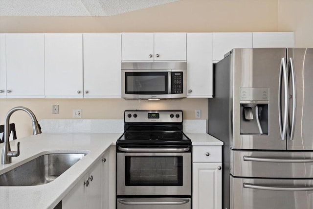 kitchen featuring appliances with stainless steel finishes, light stone countertops, sink, and white cabinets