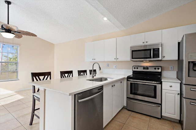 kitchen with sink, a breakfast bar area, white cabinetry, stainless steel appliances, and kitchen peninsula