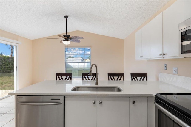 kitchen featuring lofted ceiling, sink, kitchen peninsula, stainless steel appliances, and white cabinets