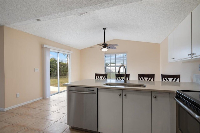 kitchen featuring vaulted ceiling, light tile patterned flooring, white cabinetry, sink, and stainless steel dishwasher