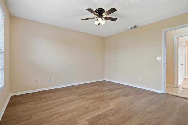 spare room with ceiling fan, a textured ceiling, and light wood-type flooring