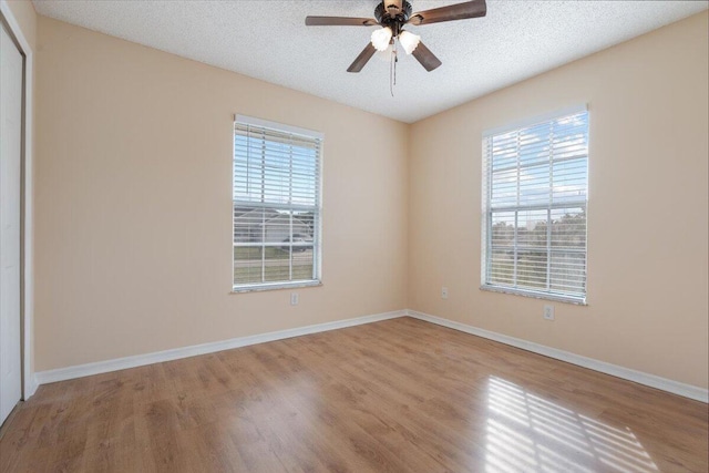 empty room with ceiling fan, a textured ceiling, and light hardwood / wood-style flooring