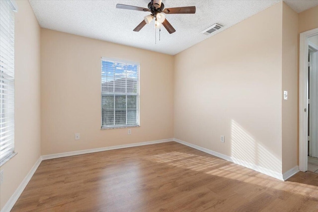 empty room with ceiling fan, hardwood / wood-style flooring, and a textured ceiling