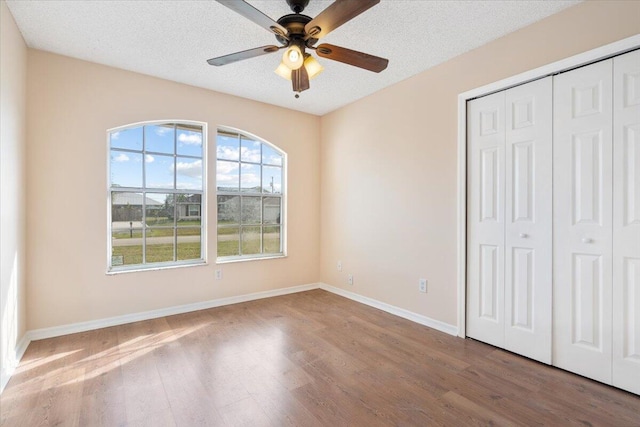 unfurnished bedroom with hardwood / wood-style flooring, ceiling fan, a textured ceiling, and a closet