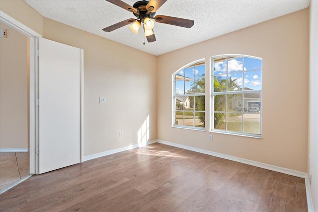 empty room featuring hardwood / wood-style flooring, ceiling fan, and a textured ceiling