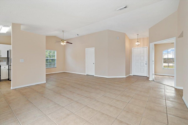 unfurnished living room with lofted ceiling, light tile patterned floors, a textured ceiling, and ceiling fan