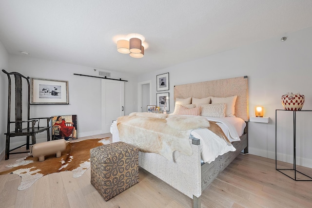 bedroom with light hardwood / wood-style floors and a barn door