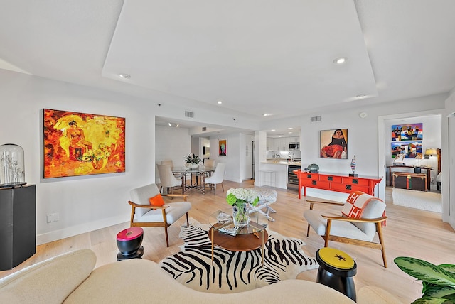 living room featuring light wood-type flooring, wine cooler, and a raised ceiling