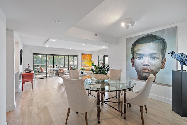 dining area with a textured ceiling and light hardwood / wood-style floors