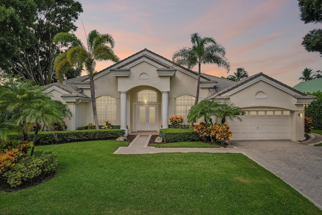 view of front of home with french doors, a yard, and a garage