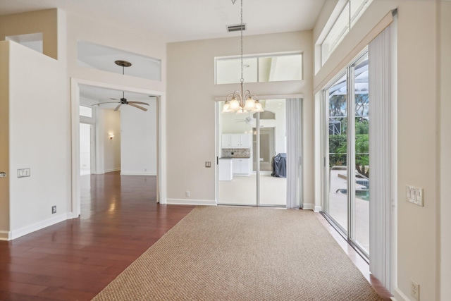 unfurnished room featuring ceiling fan with notable chandelier and dark hardwood / wood-style floors