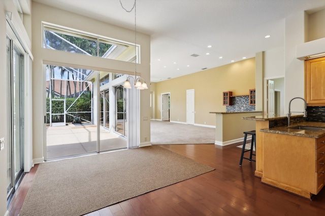 interior space featuring a high ceiling, dark wood-type flooring, a chandelier, and sink