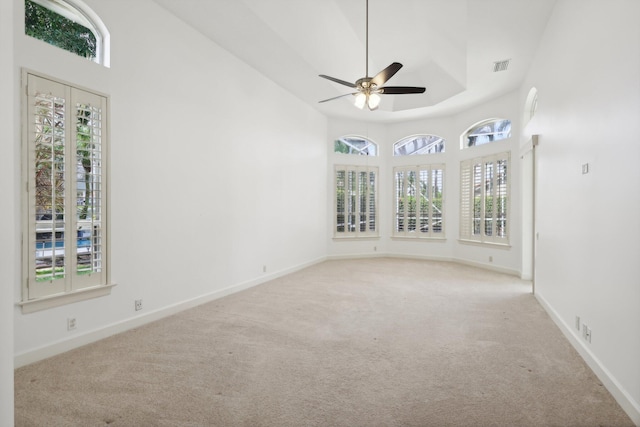 spare room featuring light colored carpet, ceiling fan, and a tray ceiling