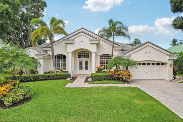 mediterranean / spanish-style house featuring a front yard, french doors, and a garage