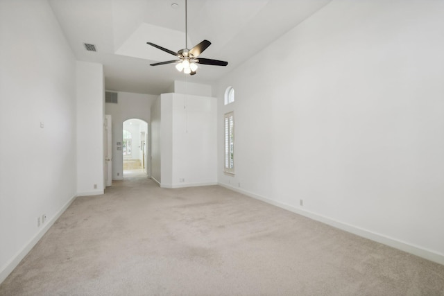 spare room featuring a towering ceiling, light carpet, and ceiling fan