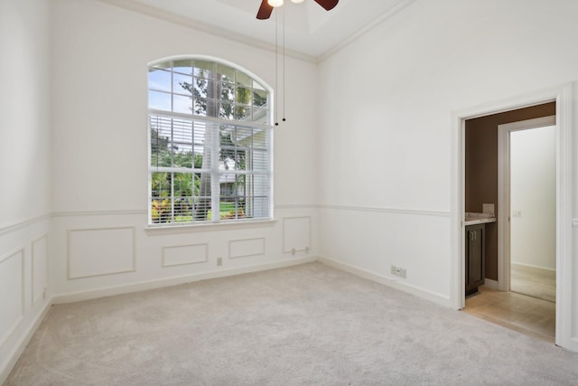 carpeted spare room with ornamental molding and ceiling fan