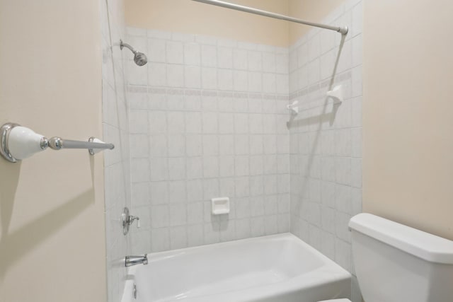 bathroom with toilet and tiled shower / bath