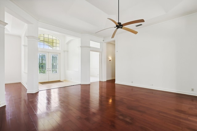 empty room with crown molding, ceiling fan, dark hardwood / wood-style flooring, french doors, and decorative columns