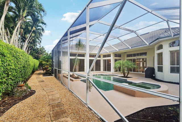 rear view of property featuring a pool with hot tub, a patio area, and glass enclosure