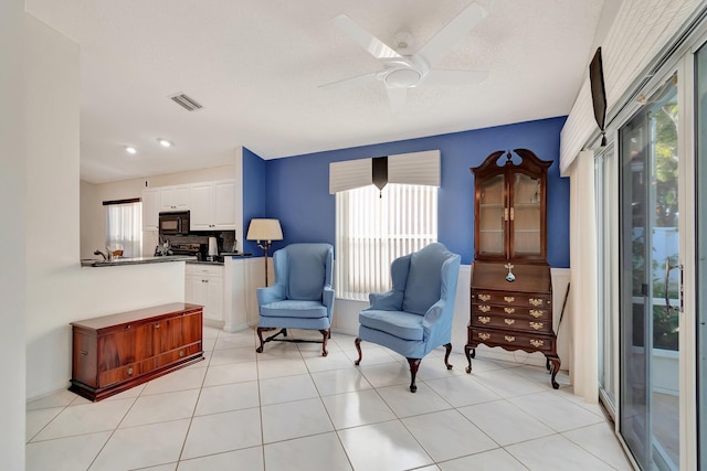 living area featuring ceiling fan, a textured ceiling, and light tile patterned floors