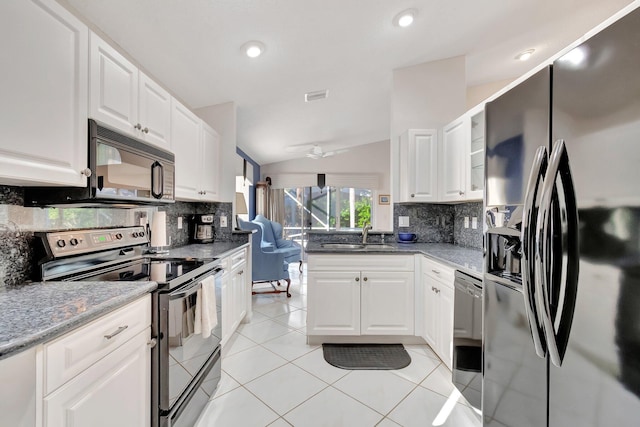 kitchen featuring lofted ceiling, white cabinets, dark stone counters, appliances with stainless steel finishes, and sink