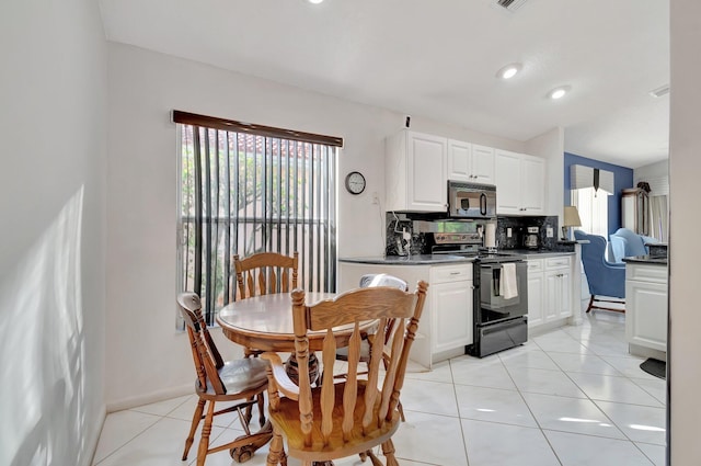 kitchen with backsplash, light tile patterned floors, black range with electric stovetop, and white cabinetry