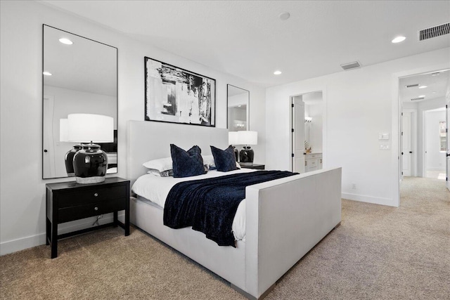 bedroom with ensuite bathroom and carpet floors