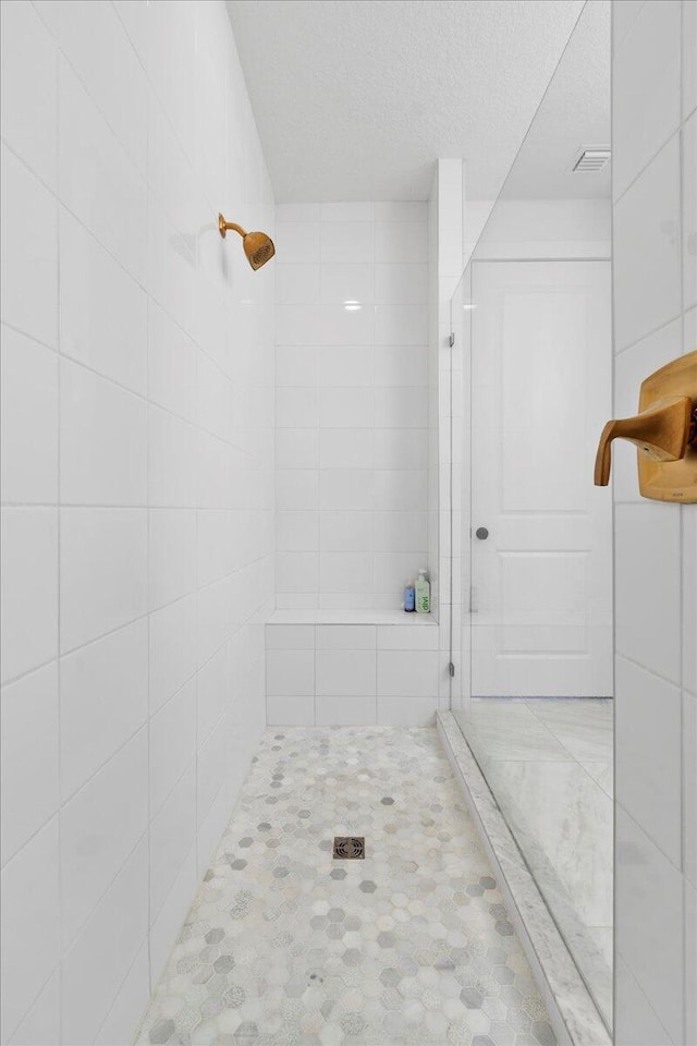 bathroom featuring a textured ceiling and a tile shower