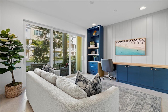 sitting room with built in desk, wood walls, light tile patterned floors, and built in features