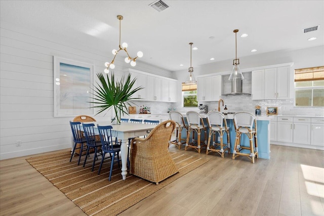 dining space with a notable chandelier and light hardwood / wood-style floors