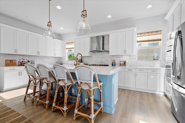 kitchen with a kitchen island, white cabinets, wall chimney exhaust hood, and hanging light fixtures