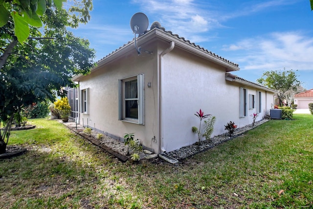 view of side of property with a yard and cooling unit