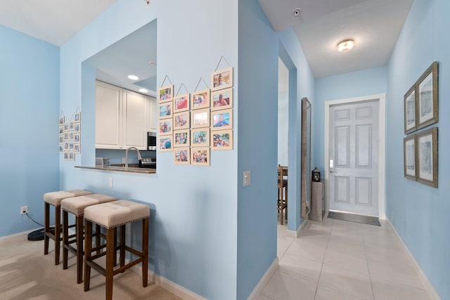 hallway featuring light tile patterned flooring and baseboards