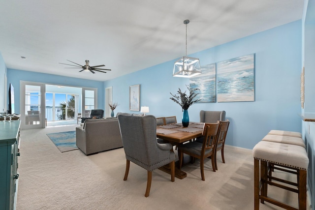 dining room with light carpet, baseboards, and ceiling fan with notable chandelier