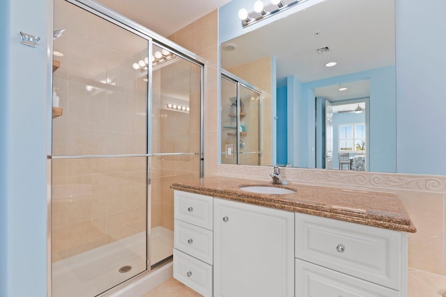 bathroom with visible vents, a shower stall, and vanity