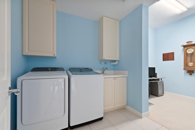 washroom featuring washing machine and clothes dryer, light tile patterned floors, cabinet space, a sink, and baseboards