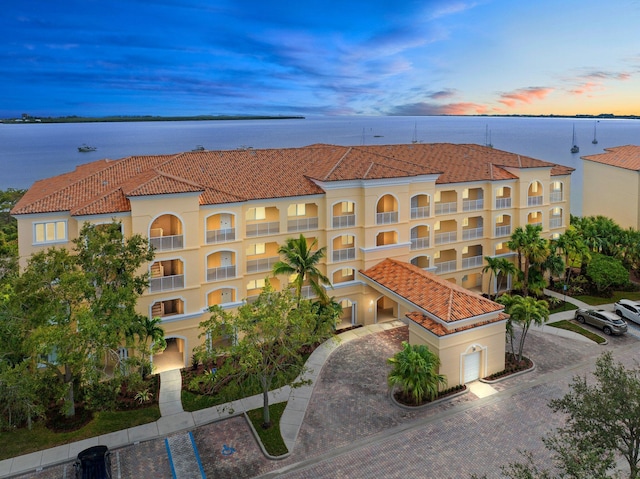 property at dusk featuring a water view and driveway