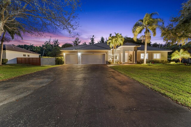 view of front of property featuring a garage and a lawn