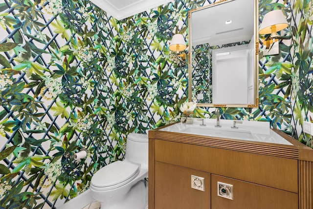 bathroom featuring toilet, vanity, and ornamental molding