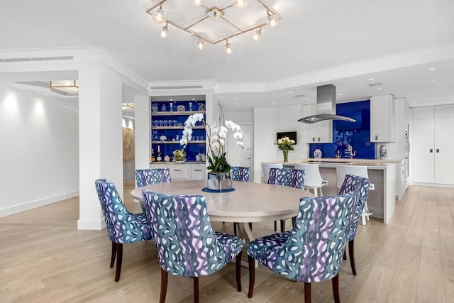 dining area featuring light wood-type flooring, an inviting chandelier, and crown molding