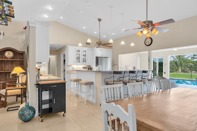 kitchen featuring white cabinetry, stainless steel fridge, high vaulted ceiling, kitchen peninsula, and ceiling fan